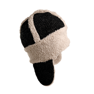 This image features the Arthur Hat, a black and beige sherpa fleece trapper hat with ear flaps. The winter hat showcases a patchwork design with alternating panels of black and beige, crafted from a fluffy, textured material designed to keep you warm in cold weather.