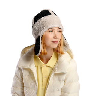 A person wearing the Arthur hat, which features ear flaps and a checkered pattern, looks to the side. They are also dressed in a white puffer jacket and a yellow shirt. The background is black.