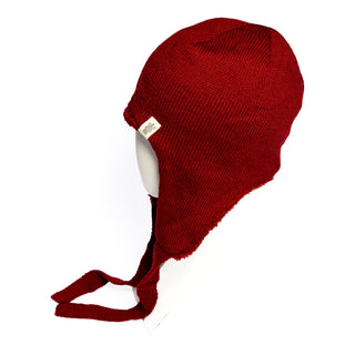 A mannequin head displays the Hand Knit Snug Hat in red, featuring cozy ear flaps and ties. This hand knit winter hat includes a small white tag on the side, and is set against a white background.