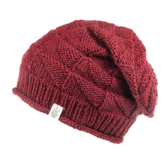 The Hand Knit Wave Slouch in red features a textured pattern and a small white tag on the brim, shown against a plain white background.