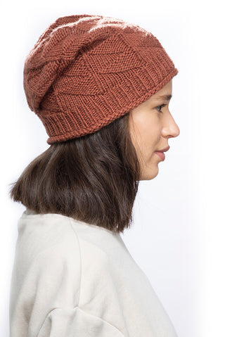 A woman wearing a brown knitted Wave Slouch made from organic cotton.