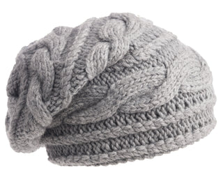 The Triple Braid Cable Slouch is a gray, chunky cable-knit beanie, hand-knit in Nepal from soft Merino wool and shown against a white background.