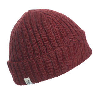The Hand Knit Clyde Rib Fold Cap in dark red merino wool is displayed on a white background, featuring a ribbed knit, folded brim, and a small white rectangular tag.