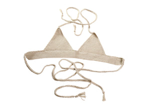 The "Bikini Top - Solid," a beige hand-crocheted bikini top, is laid flat on a white background. This elegant piece features two triangular cups and long braided straps extending from the back and neck ties, making it a perfect addition to your summer wardrobe.