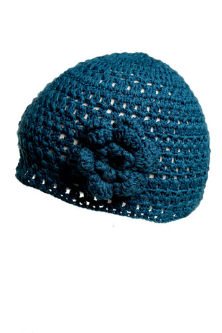 The Flower Beanie, a hand-crocheted blue beanie adorned with a decorative bloom on the side, features an open-weave design perfect for the summer collection. It is showcased against a plain white background.