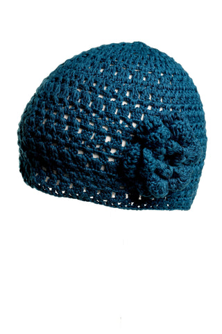 Introducing the star of our summer collection: the Flower Beanie. This blue, hand-crocheted hat showcases a textured, open weave pattern and is adorned with a decorative flower on the side. Photographed against a plain white background, its intricate design stands out beautifully.