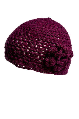 The Flower Beanie is a maroon, hand-crocheted accessory featuring a floral pattern on the front. Its open-weave design and thick yarn make it an ideal addition to your summer collection.