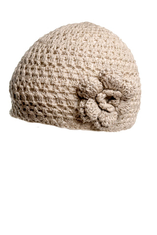 The Flower Beanie is a hand-crocheted, beige knit hat that boasts a textured pattern and an attached flower detail on one side. Designed with a snug, rounded shape and crafted from luxurious wool, this elegant piece is perfect for any season. Background is white.