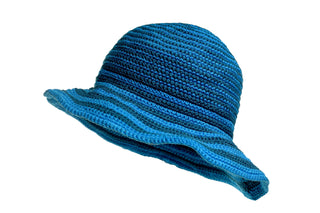 The Stripped Sun Hat is a blue, woven accessory featuring a wide, flared brim and a textured striped pattern with varying shades of blue. It appears to be lightweight and ideal for outdoor use.