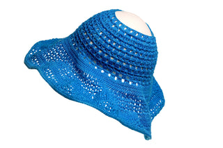 The Open Top Sun Hat is a blue crocheted accessory featuring a wide, flared brim with intricate patterns. Its soft texture and slightly wavy brim give the hat a casual, handcrafted appearance. The background of the image is plain white.