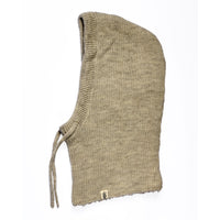 The Hand Knit Cozy Hood—a tan, ribbed balaclava—lies flat on a white background. Made from hand knit wool, it features a comfortable hooded design with two neck ties and a small rectangular tag near the hem.