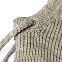 Close-up of the Hand Knit Cozy Hood in beige wool, featuring a ribbed texture with a visible shoulder seam and a narrow knitted strap, set against a white background.