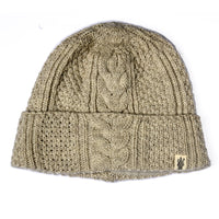 The Hand Knit Inter Hat is a beige cable knit beanie featuring a classic cable-knit pattern and a folded brim. A small rectangular fabric tag with the logo is sewn onto the brim, adding a subtle accent to this cozy winter essential.