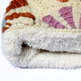 A close-up of the edge of the Hand Crochet Petal Hood, featuring a white, fluffy base with a textured, colorful pattern reminiscent of crochet daisies. The image highlights its thickness and soft pile against a plain background.