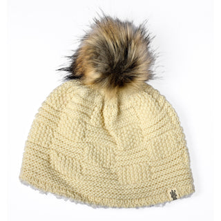 The Hand Knit Sena Hat, crafted from soft wool in a cream shade, showcases a large multicolored faux fur pom-pom on top and is presented against a white background. A small fabric tag is attached near the edge of this charming hand-knit beanie.