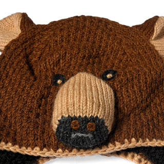 Close-up of the Hand Crochet Grizzly Hat, a wool accessory crafted to resemble a bear’s face, featuring brown and beige yarn, black crocheted eyes, a protruding snout, small rounded ears, and cozy sherpa lining for added warmth.