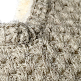 Close-up of the Hand Crochet Cloud Hood made with thick, soft yarn in beige or light gray hues, featuring a textured pattern that highlights the individual stitches and fibers. The tightly woven stitches ensure warmth and comfort, making this hand-crocheted hood ideal for staying cozy.