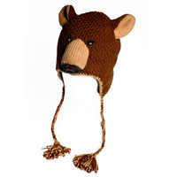 The Hand Crochet Grizzly Hat is a delightful wool creation designed to resemble a bear’s face, complete with cute ears, a snout, two button eyes, and braided tassels hanging from the sides. This unique accessory is showcased against a simple white background.