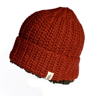 Hand Crochet Chunky Hat: A red hand-crocheted beanie with a folded brim and a small beige tag on the side, displayed against a white background. This cozy winter hat features a black-lined inside edge for extra warmth.