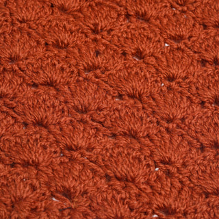 Close-up of a textured, rust-colored Hand Crochet Veil Scarf featuring a repeating pattern of raised, rounded stitches. The thick yarn has a slightly fuzzy appearance, beautifully highlighting the textured bobble stitch that adds cozy charm to this handcrafted accessory.