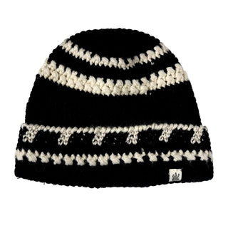 The Hand Crochet Discover Hat is a hand-knitted black beanie featuring thick cream-colored stripes and a small fabric tag on the brim. This striped fold-cuff hat has a chunky texture with a simple, repeating pattern.