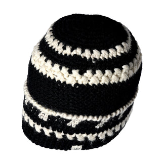 The Hand Crochet Discover Hat, crafted in a classic crochet cap style, is displayed against a plain white background. Made with chunky yarn in black and white, it features alternating thick and thin horizontal stripes and a striped fold-cuff for added warmth and comfort.