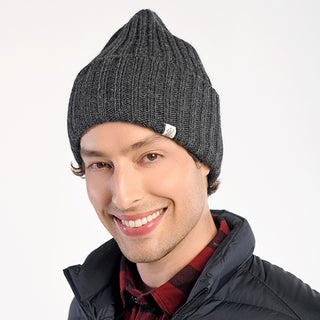 Someone wearing the Cooper Hat in dark gray, a black puffer jacket, and a red plaid shirt smiles at the camera against a plain white background.