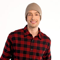 A man wearing the Hand Knit Bond Hat in beige and a red and black plaid shirt stands against a plain white background, smiling at the camera.
