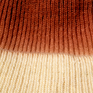 Close-up of the Hand Knit Flow Hat, showcasing its ombre design with a gradient color pattern that shifts from dark brown at the top to cream at the bottom. The clearly visible knit stitches and texture emphasize the craftsmanship of this 100% wool beanie.