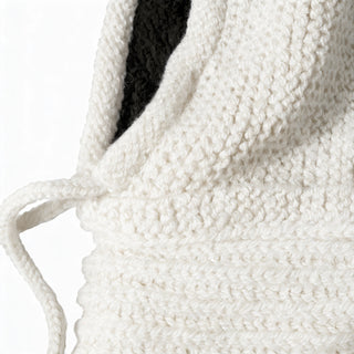 Close-up of a textured, off-white knitted fabric with a dangling string and black inner lining, featured on the Hand Knit Halo Reverse Hood.