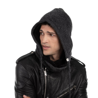 A man with dark hair looks to his left, wearing a grey Hand Loom Hero Hood over a black leather jacket, set against a plain white background.