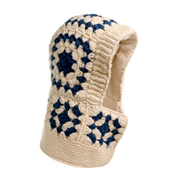 Introducing the Hand Crochet Patch Hood: a hand-crocheted wool balaclava showcasing cream and navy blue granny square patterns, featuring an open face design and lined with a soft, light sherpa material. Displayed against a plain white background.