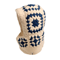 The Hand Crochet Patch Hood is a cream and navy blue hand-crocheted wool accessory featuring a classic granny square pattern in a striking geometric design. Covering both the head and neck, it stands out beautifully against a plain white background.