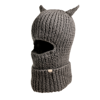 The "Hood With Horns" is a handcrafted wool balaclava with a ribbed texture in grey. This winter accessory features two small, pointed ear-like protrusions at the top, and includes a single horizontal opening for the eyes along with a folded brim at the bottom.