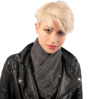 A person with short blonde hair wearing a black leather jacket and a gray hand-knit Soft Wool Rib Knit Pretty Neck Warmer, looking to the side with a neutral expression against a white background.