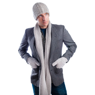 A man dressed in winter clothing including a beanie, Marbled Scarf handmade in Nepal, gloves, and a coat, standing against a white background with his hands in his pockets.