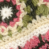 Close-up of a crocheted fabric with green, white, pink, and cream yarn—perfect for Dreams Hand Crochet Handwarmers. Detailed stitches highlight the handmade floral design and cozy texture.