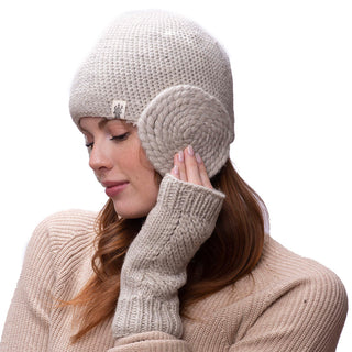 A woman wearing diagonal knit handwarmers and a fleece-lined sweater with her eyes closed, gently touching her ear-covering with her right hand.