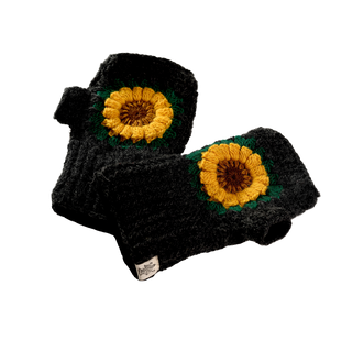 A pair of Sunflower Handwarmers, hand-knit in black with a ribbed texture, featuring a yellow sunflower design on the back of each glove and an attached white label.