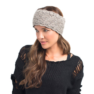 A woman with long brown hair wearing a Lacey headband and a handmade wool sweater with cut-out details.