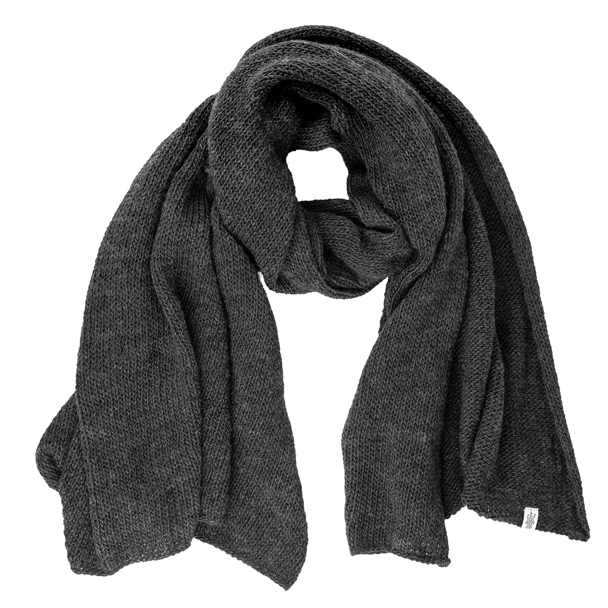 The Hand Loom Air Wrap Scarf in dark gray merino wool is laid flat with a loose, circular fold at the center, its ends draped to the sides and a small white fabric tag near one end.