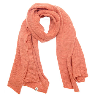 The Hand Loom Air Wrap Scarf, made of textured merino wool in muted coral, is loosely folded on a white background with a small fabric tag near one end.