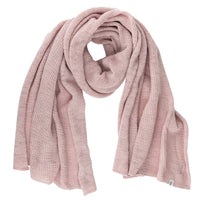 The Hand Loom Air Wrap Scarf, in light pink merino wool, is displayed on a white background. It looks soft, cozy, and thick with folded loose ends and a small tag attached to one end.