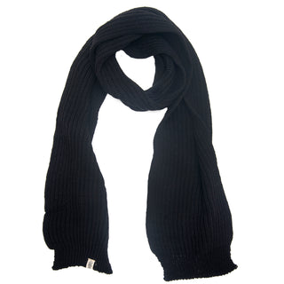 A long, ribbed, black Hand Loom Laurent Scarf made from merino wool is laid flat on a white background, featuring a small white tag near one end.