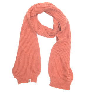 The Hand Loom Laurent Scarf is handmade in Nepal from ribbed merino wool, shown here in a muted coral shade with a small tag near one end, laid flat on a white background.
