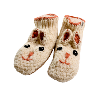 Rabbit Slippers: A pair of hand-knit wool slippers designed to resemble rabbits, featuring stitched black eyes, pink noses, and ears with a pink inner lining. These cozy winter footwear options have a warm, textured appearance perfect for chilly days.