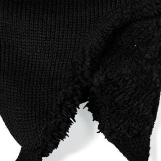 Close-up of a black textured fabric with a knit pattern on one side and a soft, fuzzy, fleece-like material on the other—perfect for keeping warm in winter. The two textures meet at an uneven edge, similar to what you’d find in the cozy Hand Knit Snug Hat.