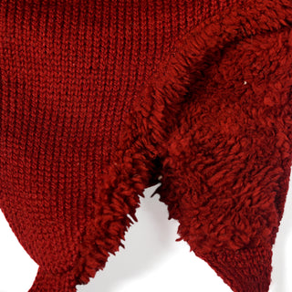 Close-up of a red fabric with a knitted texture on one side and a soft, fuzzy texture on the other, highlighting the contrast between the two materials—just like you’d find in the Hand Knit Snug Hat, designed for cozy comfort in colder weather.
