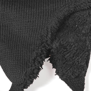 A close-up of the Hand Knit Snug Hat’s black fabric highlights its cozy construction, with one side featuring smooth knitted stitching and the other side displaying a fuzzy, fleece-like texture—perfect for keeping warm in winter.