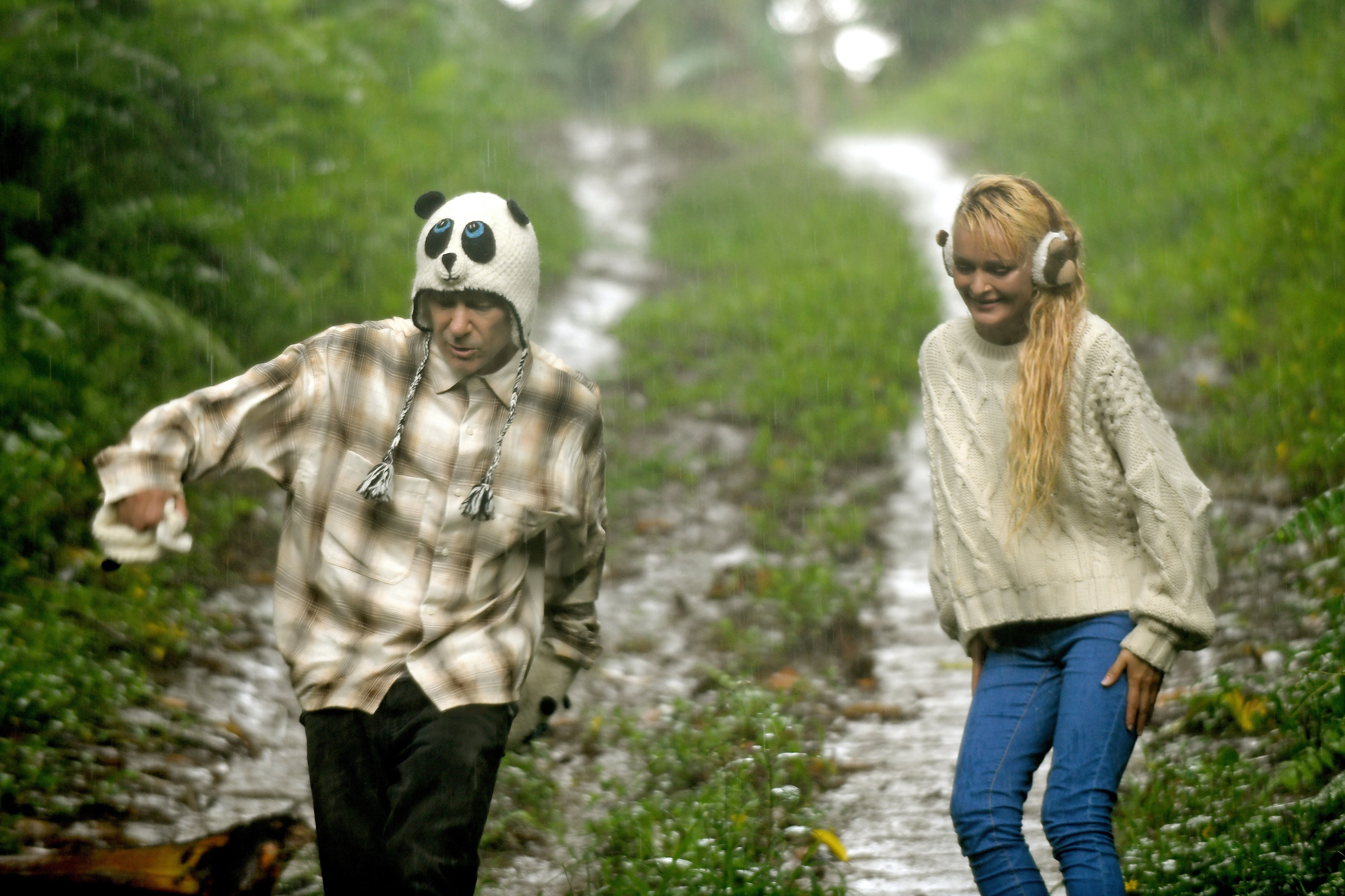 Couple walking in the rain wearing a panda hat and animal earmuffs